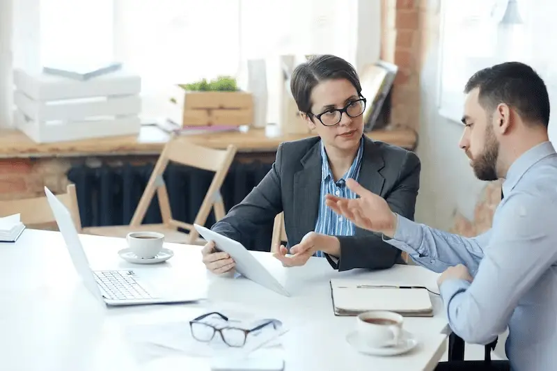 Business professionals discussing strategy during a consulting meeting with a laptop and tablet on the table