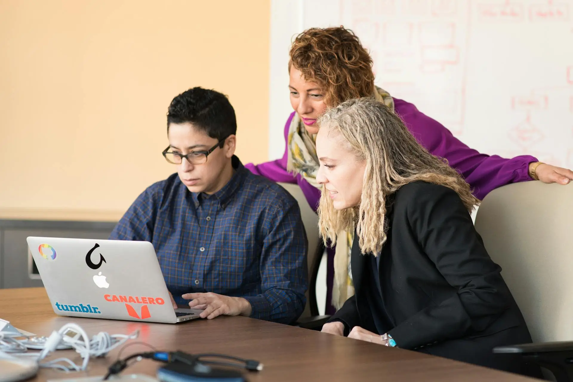 Team collaborating and discussing strategies on a laptop in an office setting at Pearl Lemon Consulting.