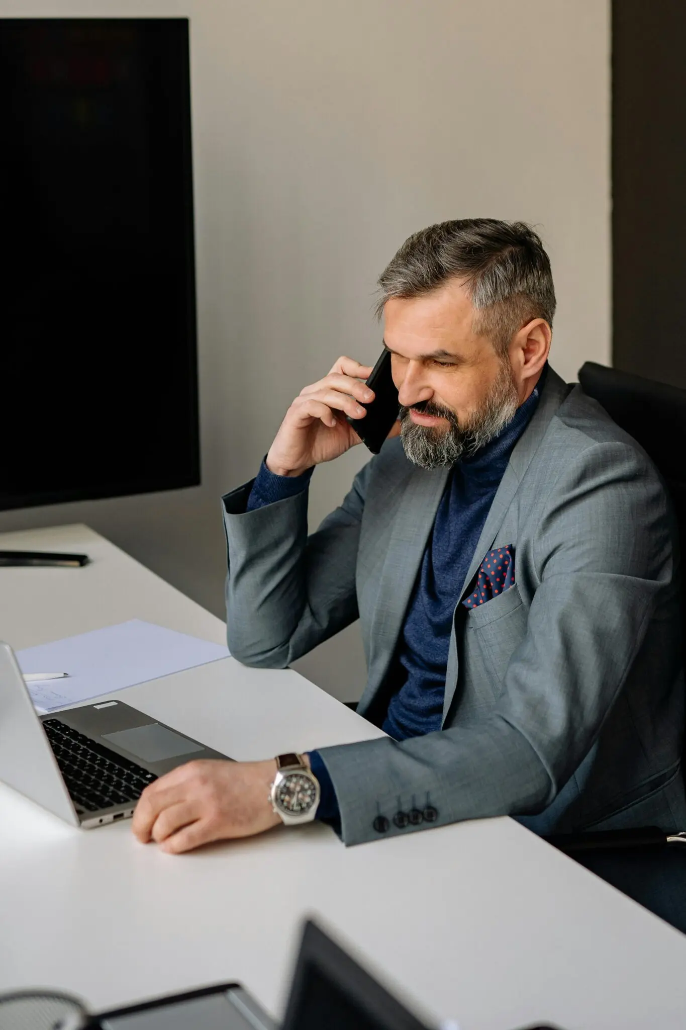 Talent Development and Leadership professional in suit on phone in office with laptop