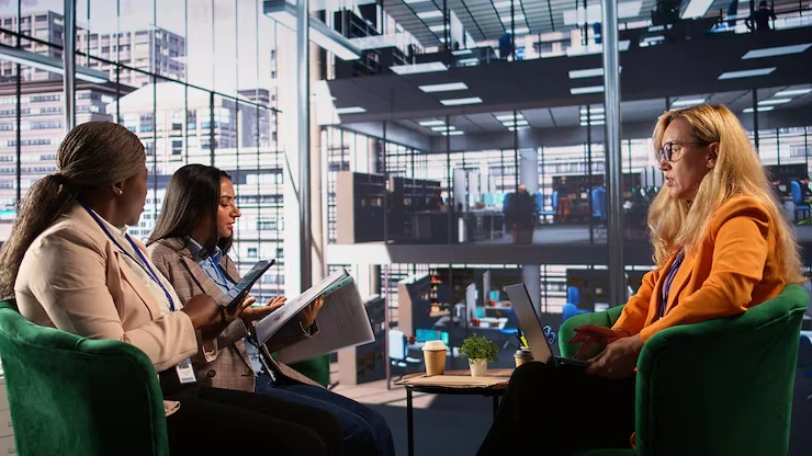 Three professional women business consultants meeting in modern office discussing startup management consulting services