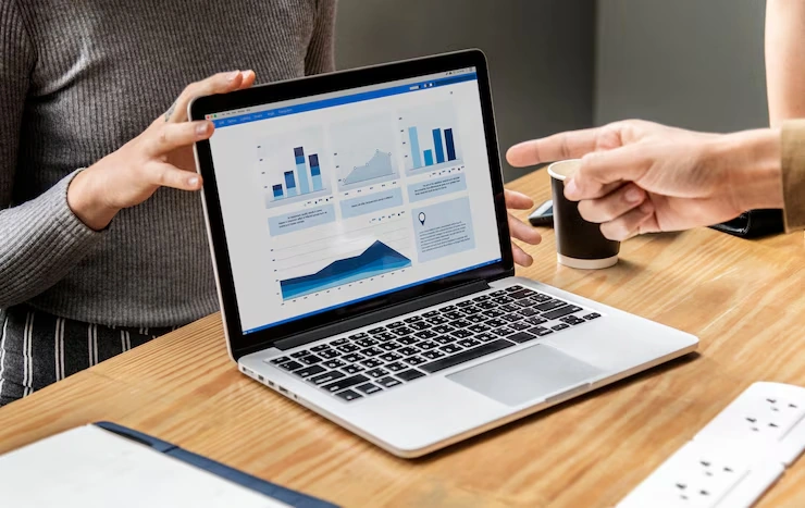Two people discussing Google Analytics dashboard with charts and graphs on laptop for consultancy services
