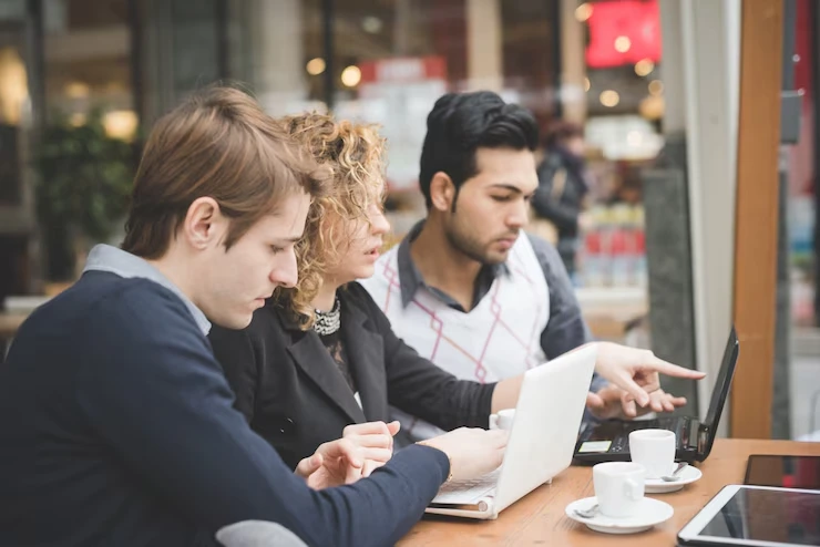 Three business professionals collaborating on digital strategy consultation at London cafe meeting