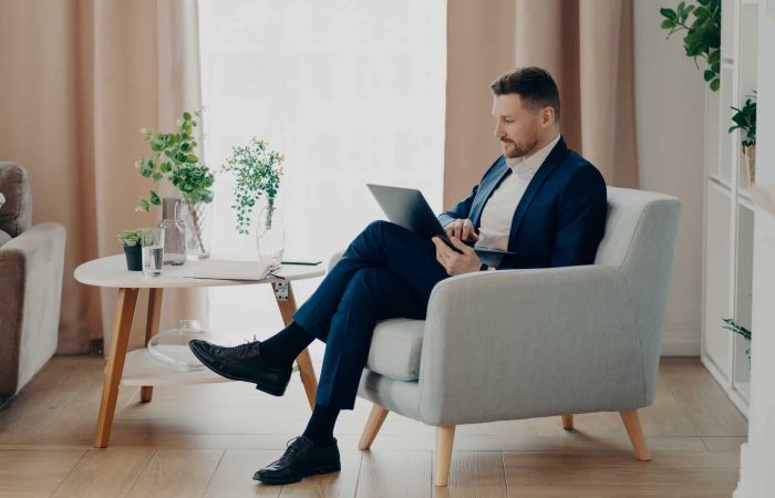 Concentrated man in suit typing on laptop in living room