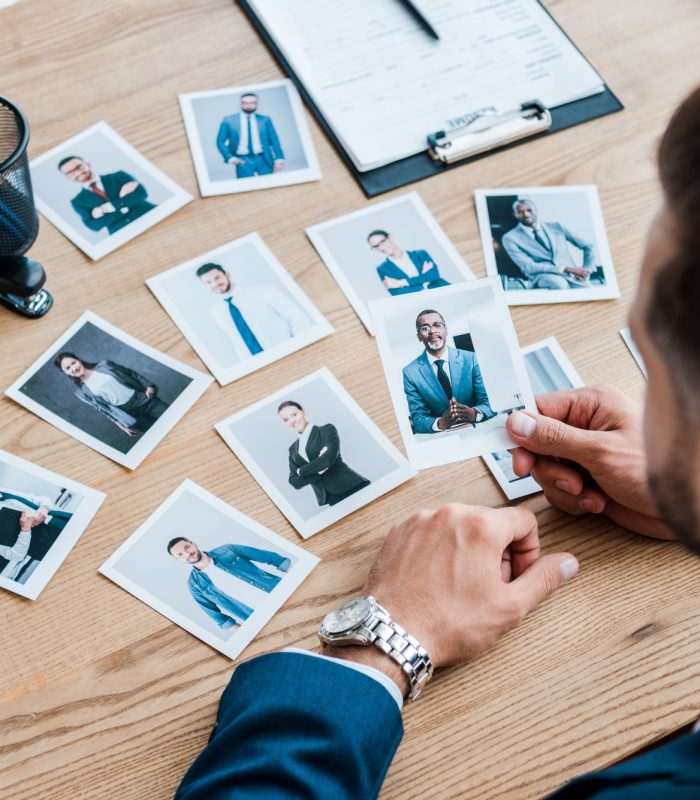 selective focus of recruiter holding photo of african american man on wooden table