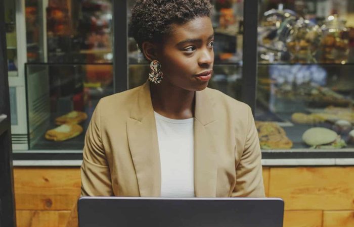 Smiling Black woman sitting at table with laptop in cafe