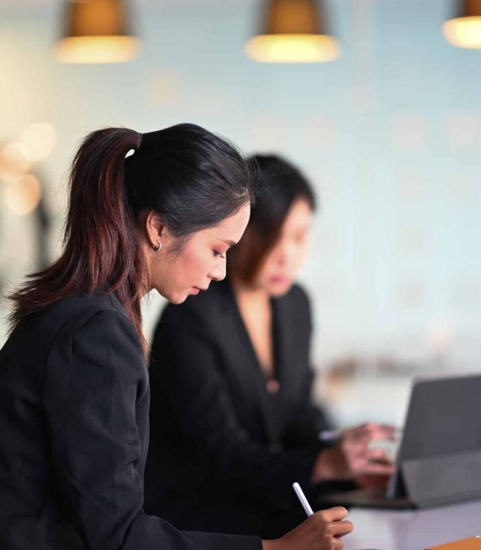 Two female colleagues in office co working and working with tablet computer.
