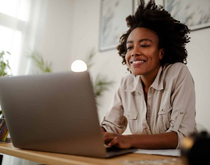 Young black smiling woman working at computer in an office.