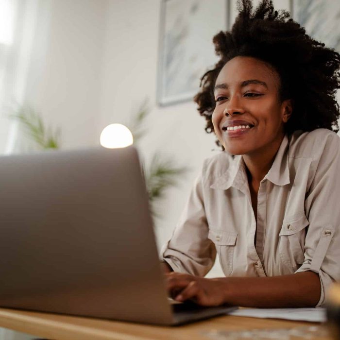 Young black smiling woman working at computer in an office.
