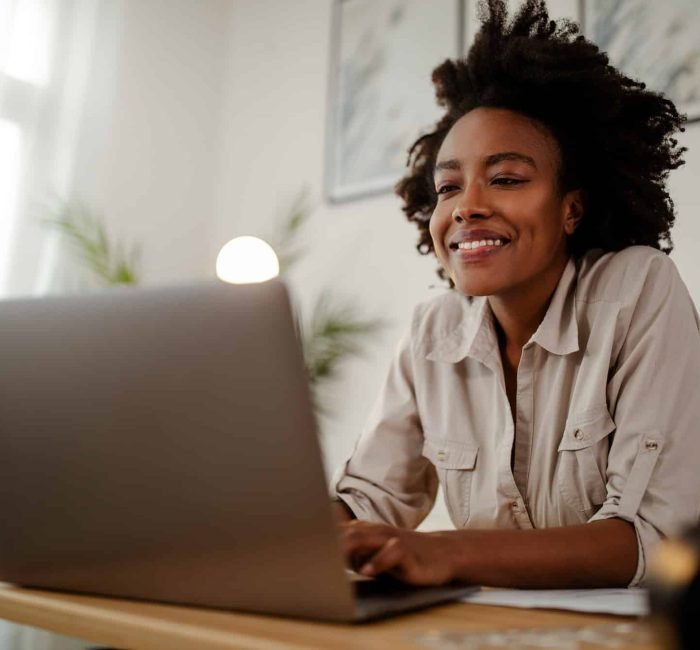 Young black smiling woman working at computer in an office.
